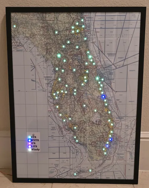 A framed Florida sectional map with lights along the coasts, green and blue