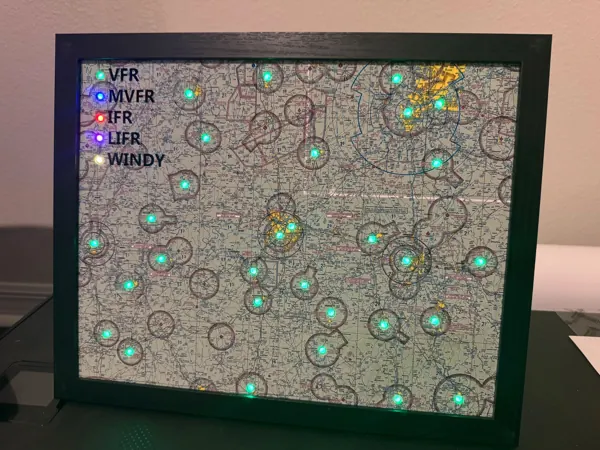A framed sectional map with green airport lights and a lit legend, on a desk