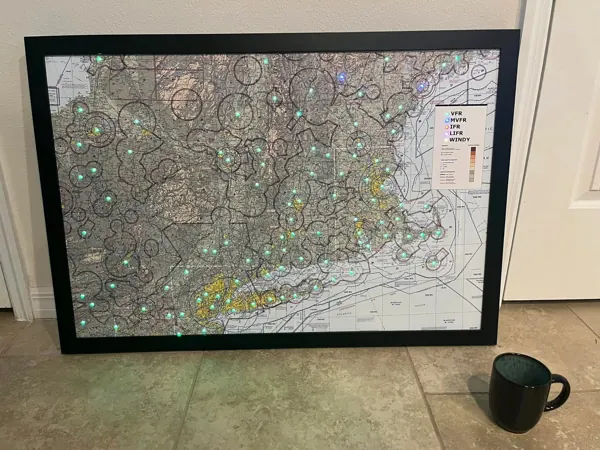 A framed map with lights at each airport, on the floor next to a coffee mug