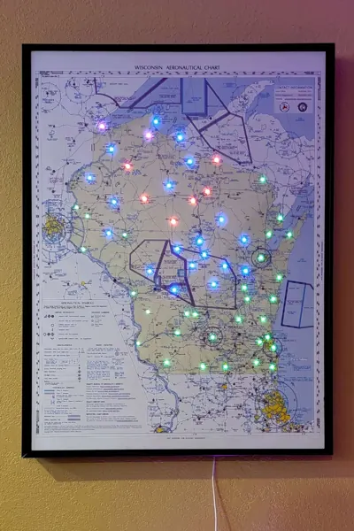 A tall framed sectional map with colored airport lights
